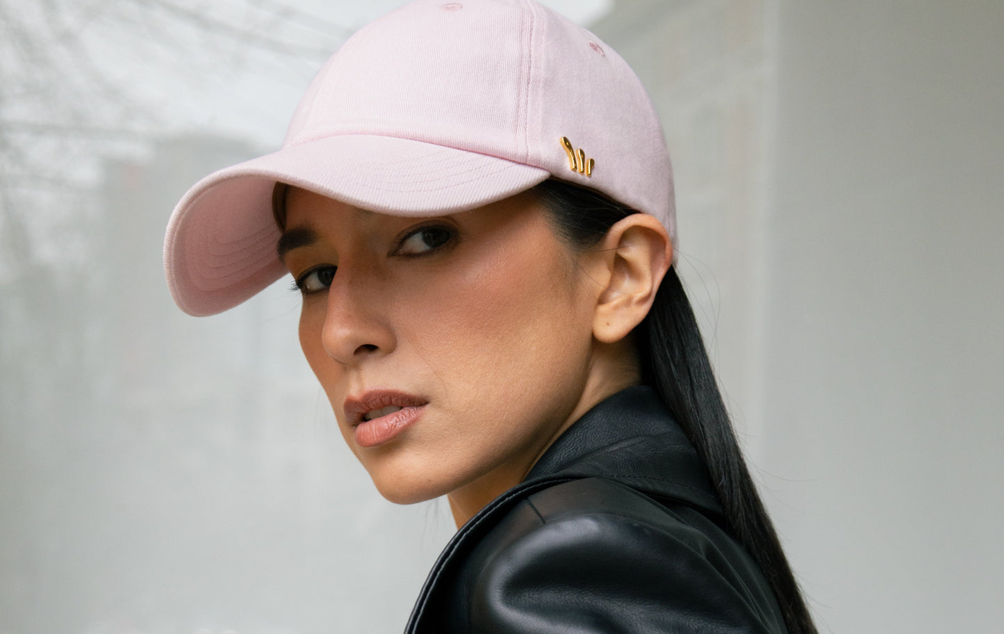 Person wearing a black leather jacket and pink chord cap against a light background