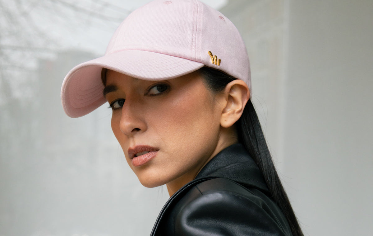 Person wearing a black leather jacket and pink chord cap against a light background